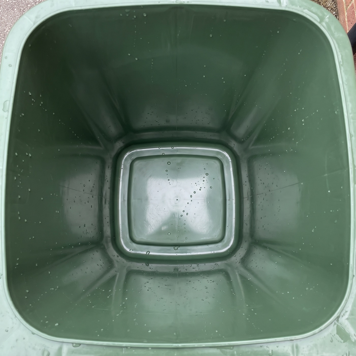 Binnenkant van een proper gewassen groene bak met waterdruppels