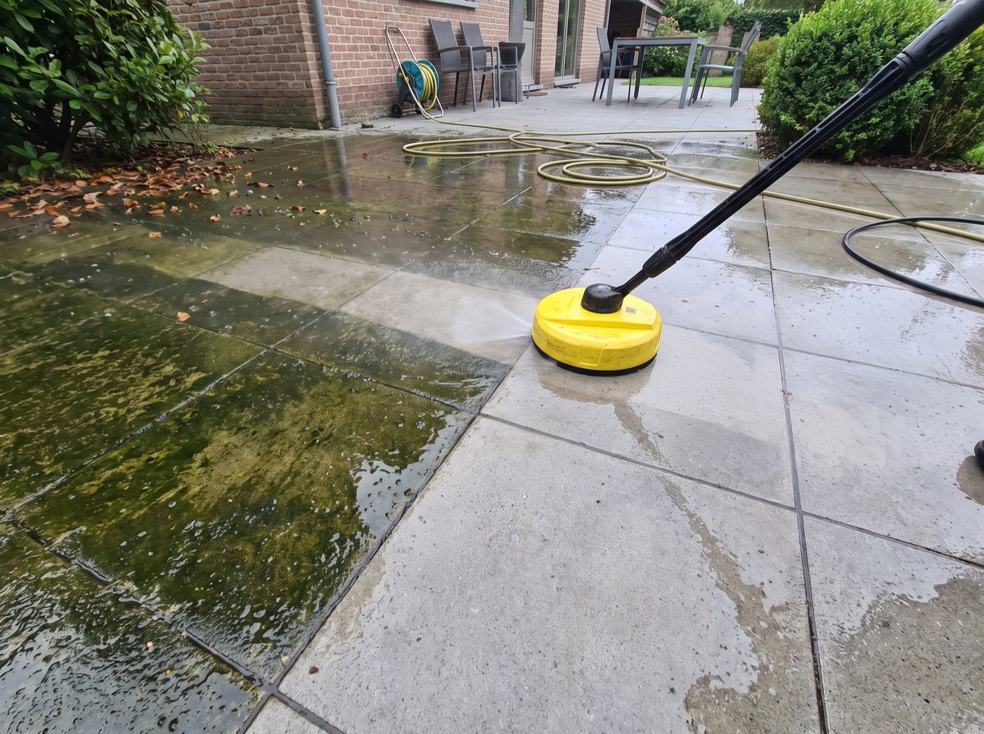 Terrastegels half schoongemaakt: links groen van het mos, rechts weer lichtgrijs